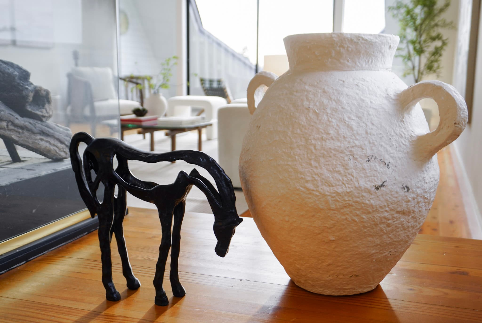 Staging detail in a Kirkland home — a black horse sculpture beside a white textured vase on a wood table, the living room beyond